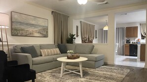 A living room with a grey sectional sofa, a round coffee table, and a painting on the wall.