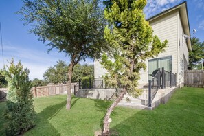 A modern house with a well-maintained lawn, a wooden fence, and a small tree.