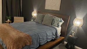 A bedroom with a bed, bedside tables, a lamp, and a wall decoration.