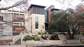 A modern building with a stone facade, a small waterfall feature, and a surrounding garden with a stone pathway.
