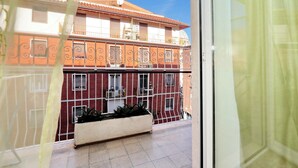 Udsigt til en bygning med balkon, parabol og et vindue med gardin.