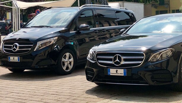 To sorte Mercedes-Benz biler parkeret på en belagt overflade.