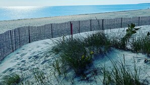A sandy beach with a wooden fence and sparse vegetation.