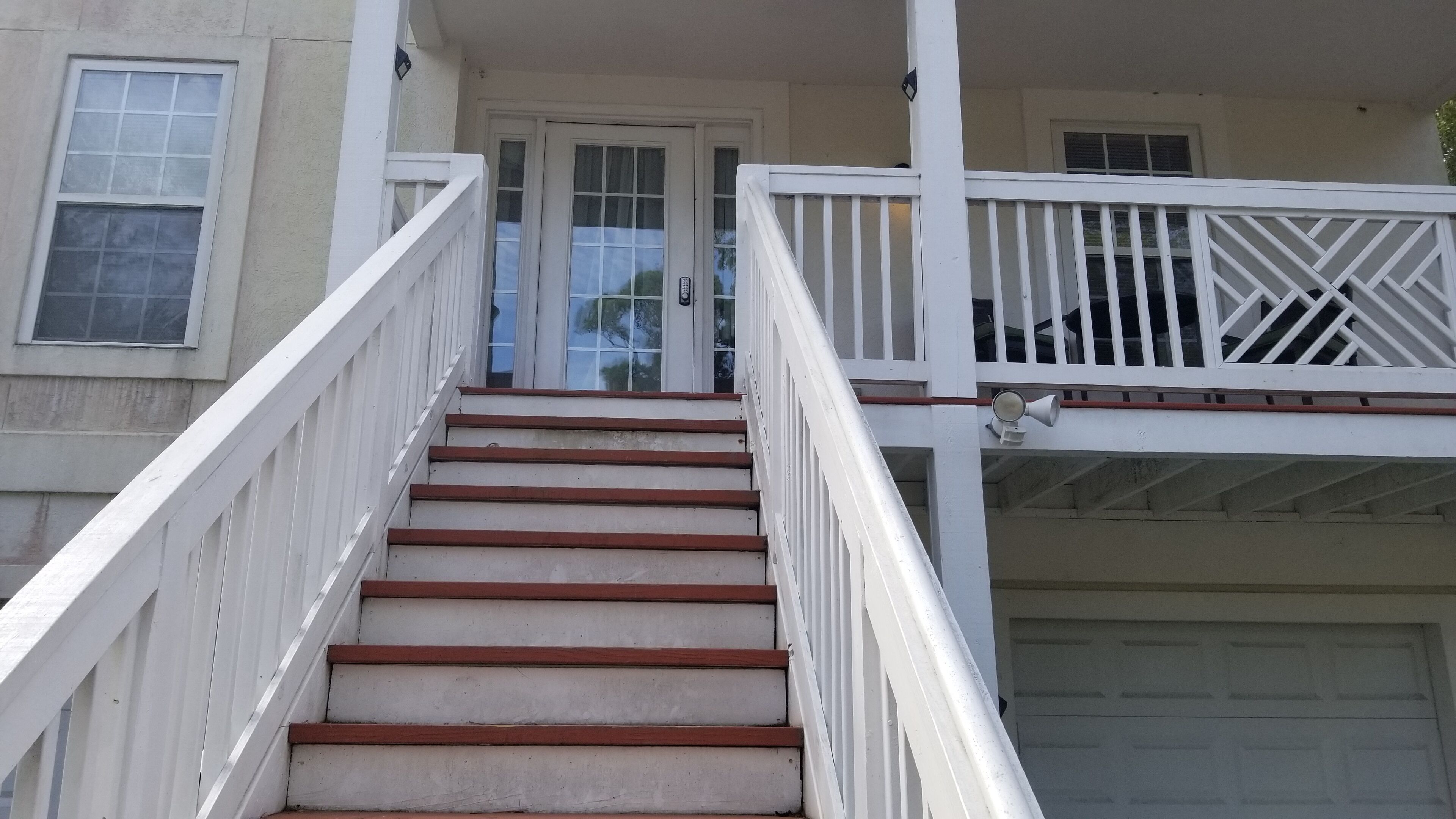 A staircase with white railings leading to a door.