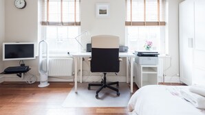 A bedroom with a bed, a desk with a chair, a computer, and a TV. - Cozy Fitzrovia studio on a quiet cobbled street in the West End! (London)