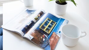 An open magazine on a table with a plant and two white mugs. - Cozy Fitzrovia studio on a quiet cobbled street in the West End! (London)