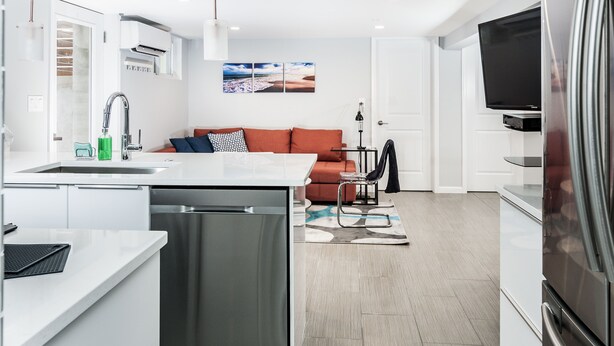 Eine moderne Küche mit Geschirrspüler, ein Essbereich mit Tisch und Stühlen, eine Sitzecke mit Sofa und ein Flachbildfernseher.
