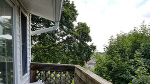 En træterrasse med et espaliergelænder, to træstole og en glasdør, der fører ind til et rum.