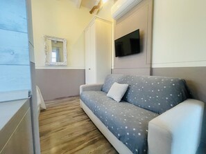 Une pièce comprenant un canapé, un téléviseur fixé au mur, un miroir et une armoire.