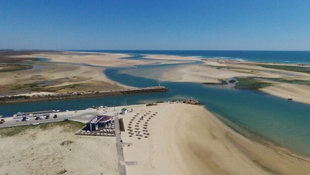 An aerial view of a coastal area with a sandy beach, a marina with boats, and a pier extending into the water. - Algarvian House - Arroteia "Carpenter Houses" (Tavira)