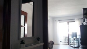 A modern living room with a large mirror, a small shelf with plants, and a view into a dining area. - Apartment/ flat - AyamonteResidential flat (Ayamonte)