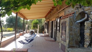 Un espace extérieur abrité, doté d’une pergola, de murs en pierre et d’un sol en briques.