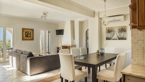 Un comedor moderno con una mesa de madera oscura, sillas blancas, una chimenea y un televisor montado en la pared.