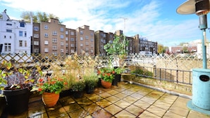 Une terrasse sur le toit, agrémentée de plantes en pot et offrant une vue sur la rue.