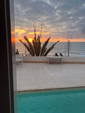 A poolside view with a sunset over the ocean, a white tiled deck, and a few lounge chairs. - Oceanfront villa near Agadir, private pool! Sidi Ifni (Sidi Ifni)