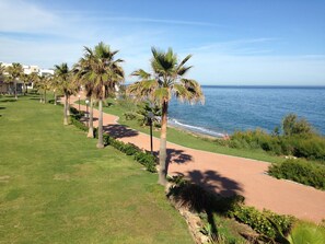 A coastal walkway with palm trees, a beach, and a clear sky. - LUXURIOUS APARTMENT NEAR THE BEACH WITH SEA VIEWS IN ESTEPONA (Estepona)