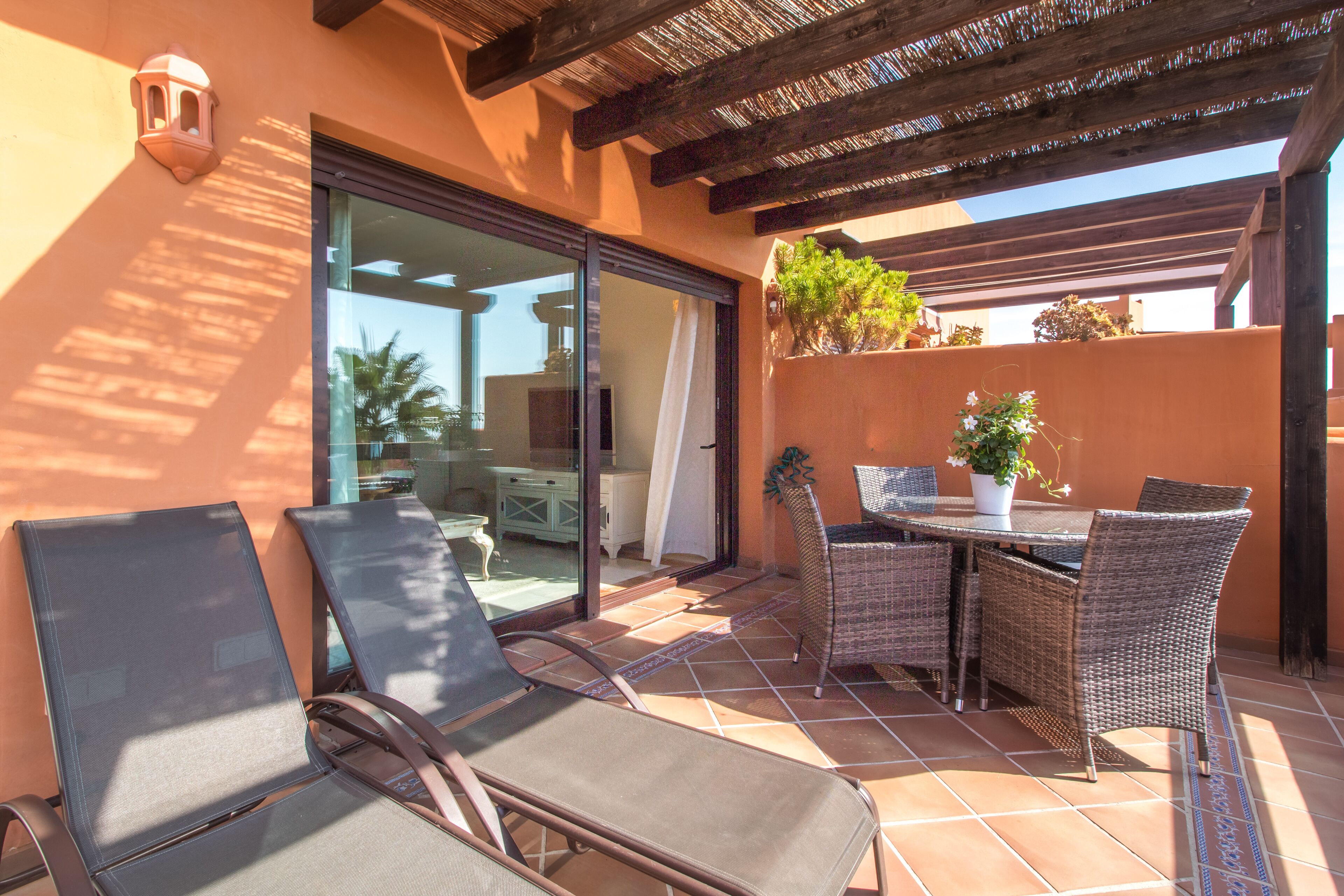 A patio with wicker furniture, a table, and chairs.