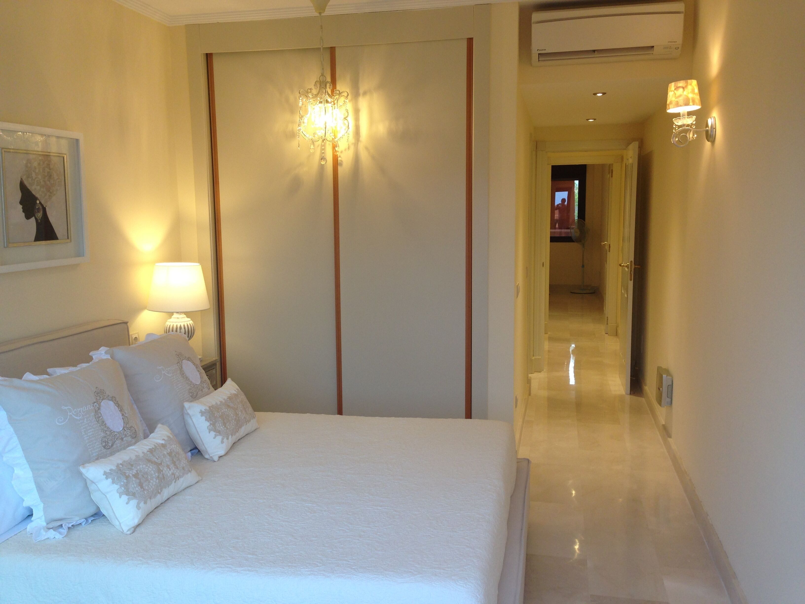 Una habitación de hotel con una cama grande, una araña y una lámpara de pared, además de un cuadro enmarcado.