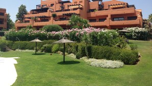 Un hôtel doté de nombreux balcons, d’un jardin bien entretenu avec diverses plantes et fleurs, et d’un ciel dégagé.