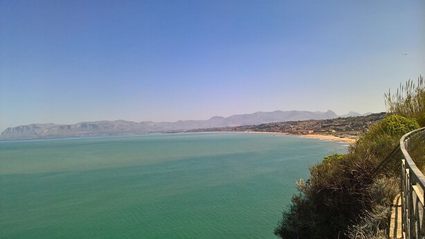 Un paisaje costero con vista despejada al mar, una playa y montañas a lo lejos.