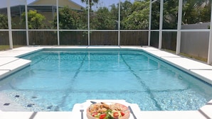Una piscina con una mesa y un plato de comida al frente.
