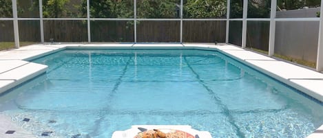 A swimming pool with a table and a plate of food in the foreground.