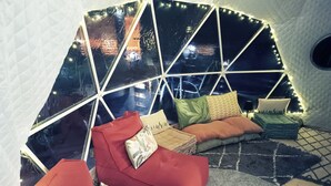 Een gezellig interieur met een geometrisch raamontwerp, een rode bank en een kamerbreed tapijt.