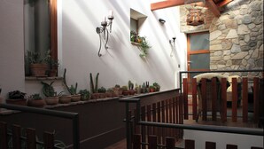 Een balkon met terracotta potten, een stenen muur en een houten hek.