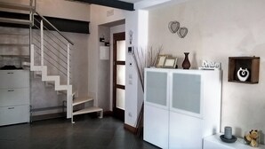 Een modern interieur met een trap, witte kasten en decoratieve objecten.