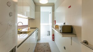 A modern kitchen with a stainless steel sink, a built-in oven, and a microwave. There is a small shelf with a toaster and a fire extinguisher. - Hipster´s dream by the river (Porto)