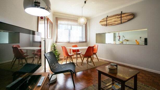 A modern living room with a dining area, a kitchen with a built-in oven, and a large window providing natural light. - Hipster´s dream by the river (Porto)