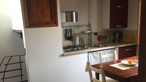 A kitchen with a wooden table and chairs, a gas stove, and cabinets.