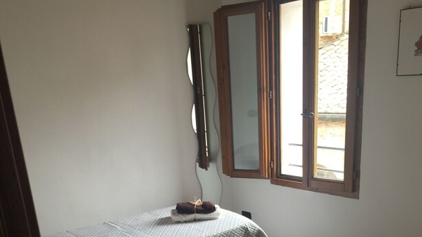 A bedroom with two beds, a mirror, and a window.