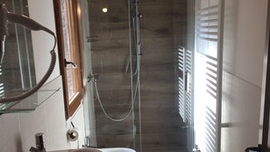 A modern bathroom with a large sink, two toilets, a shower, and a glass door leading to a shower area.