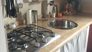 A kitchen with a gas stove, stainless steel sink, and various kitchen utensils.