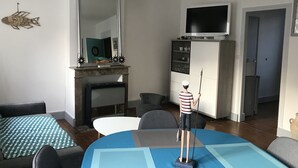 Un salon comprenant un téléviseur, une cheminée, un coin repas et une statue représentant une personne tenant une canne à pêche.