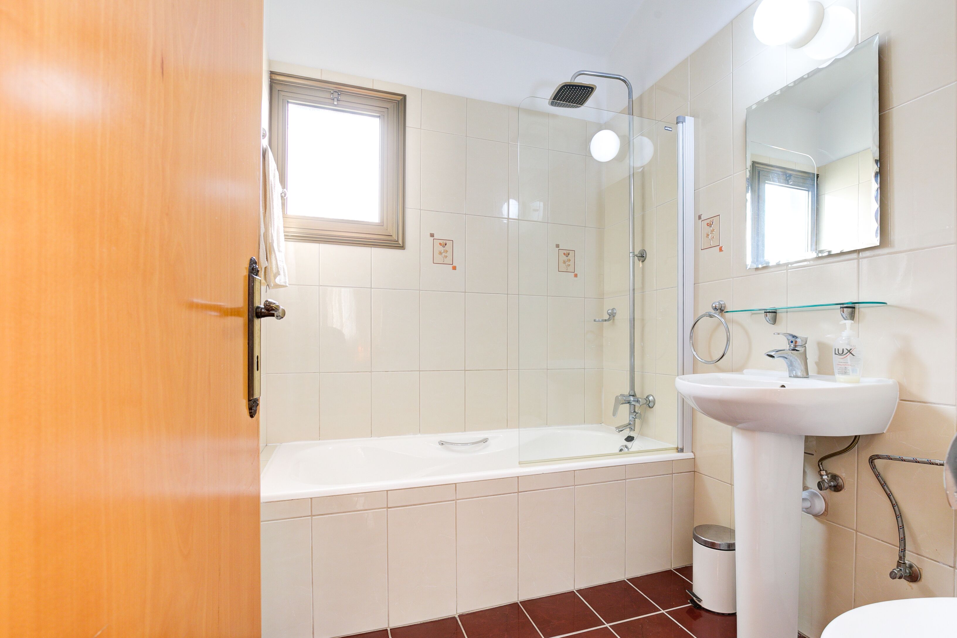 A bathroom with a bathtub, a sink, a mirror, and a window.