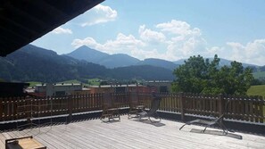 A wooden deck with outdoor seating and a view of mountains and buildings. - Haus Susanne - self-catered Guest House Apartment. (Radstadt)