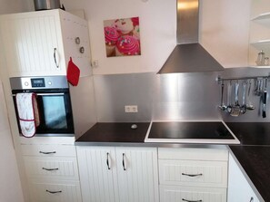 A kitchen with white cabinetry, a stainless steel range hood, and a black countertop. - Haus Susanne - self-catered Guest House Apartment. (Radstadt)