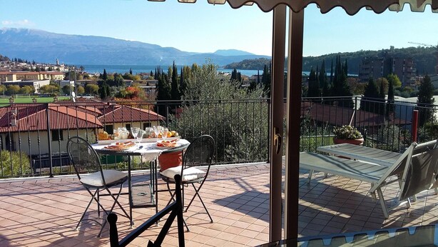 Eine Terrasse mit Esstisch und Blick auf eine malerische Seen- und Berglandschaft.