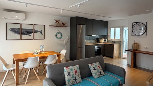 Una sala de estar moderna con sofá, mesa de comedor y zona de cocina.