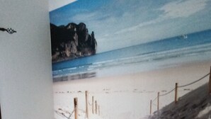 A bedroom with a bed, a nightstand, and a wall mural of a beach scene.