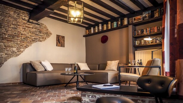A cozy living room with a brick wall, a sofa, a coffee table, and a bookshelf.