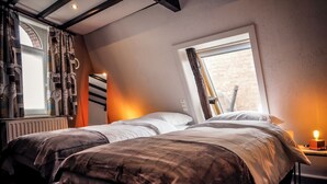 A bedroom with two beds, a window with a view, and a radiator.