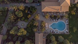 Vista aèria d'un complex tur ístic amb piscina, gandules i palmeres.
