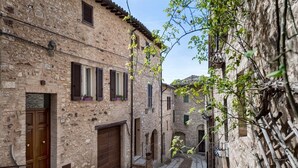 A narrow cobblestone street flanked by historic stone buildings with arched doorways and wooden shutters. - Villa Elisa Historical residence Welness (Spello)