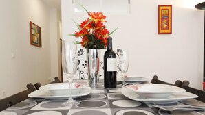 Une table à manger dressée avec des assiettes, des verres, une bouteille de vin et un vase de fleurs.