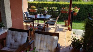 Une terrasse extérieure avec une table et des chaises en bois, un canapé rembourré et des plantes en pot.