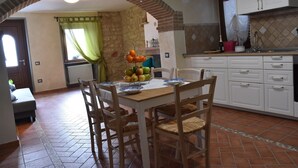 Una cocina con armarios blancos, piso de baldosas y una mesa de comedor con sillas.