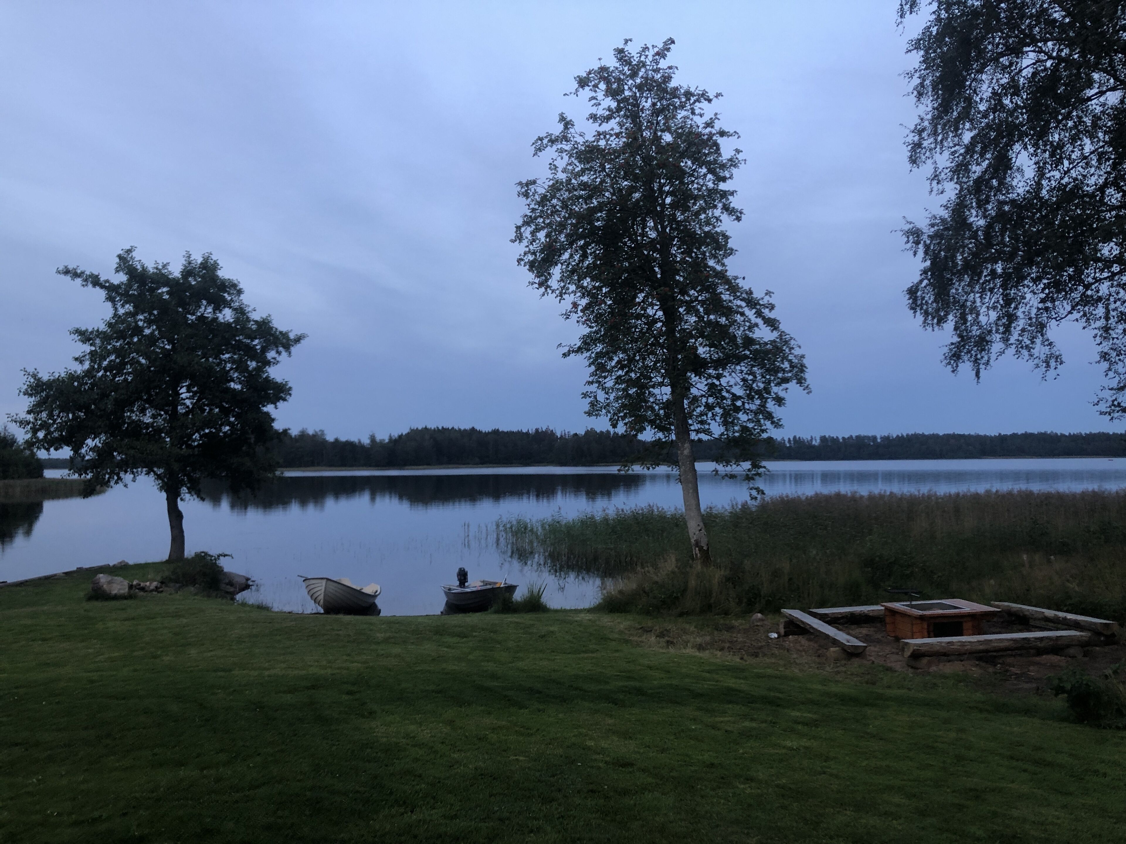 A lakeside scene with boats, a wooden structure, and trees.